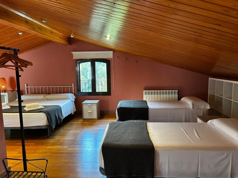 Attic with several beds under the sloping wooden ceiling