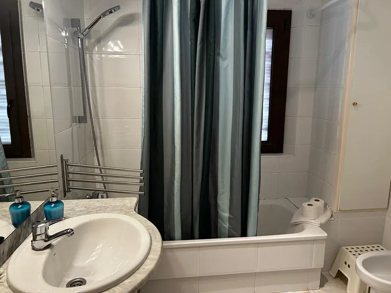 First-floor bathroom with a bathtub, curtain and window