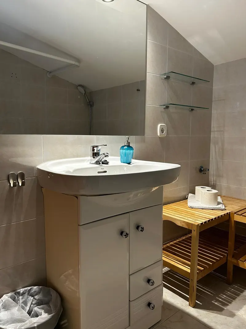 Attic bathroom with a washbasin, mirror and wooden shelf