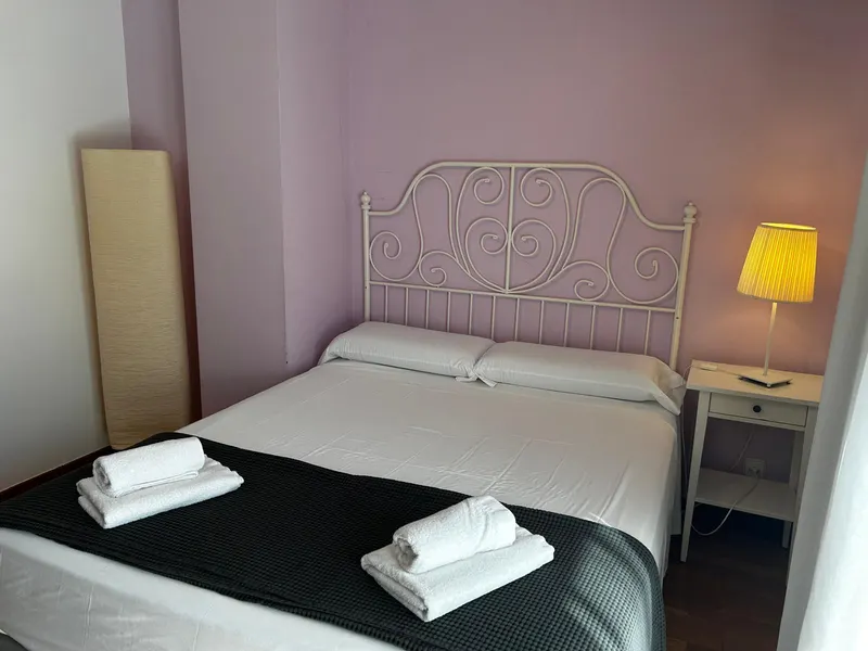 Pink double bedroom: double bed with a white wrought-iron headboard