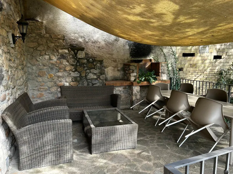 Zona chill sota la vela d’ombra, amb sofàs, taula i cadires