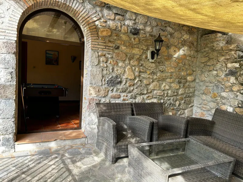 Porch sofas beside a stone wall and an arched door