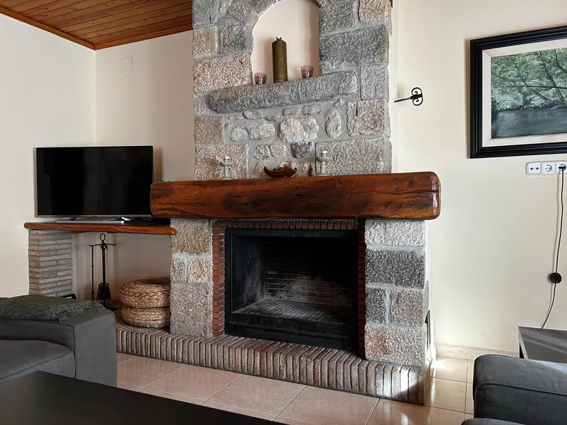 Stone fireplace with a wooden beam and a TV