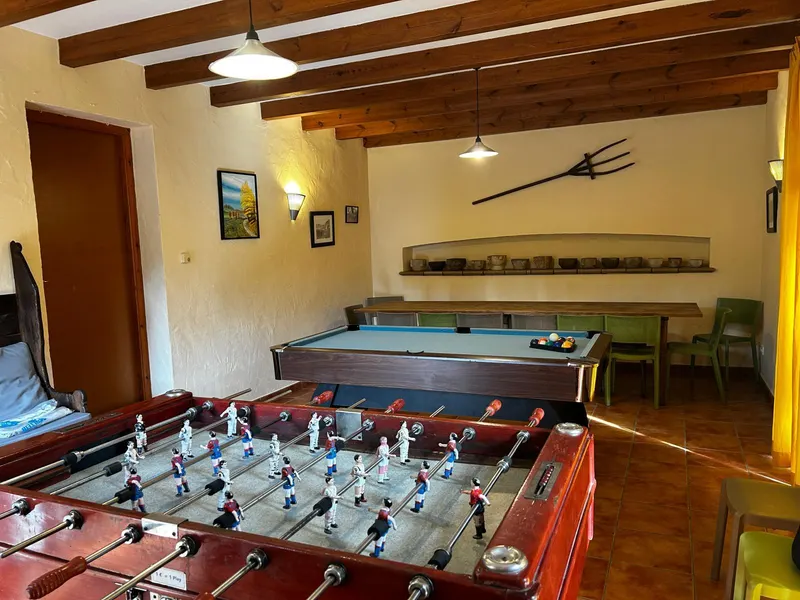 Vista general de la sala de jocs amb futbolí, billar i taula llarga