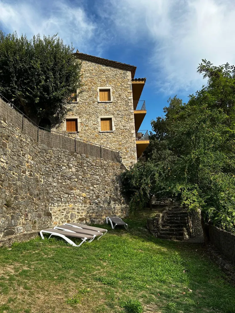Lawn with sun loungers below the stone house