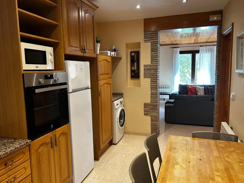 Kitchen with oven, microwave and fridge, opening onto the living room