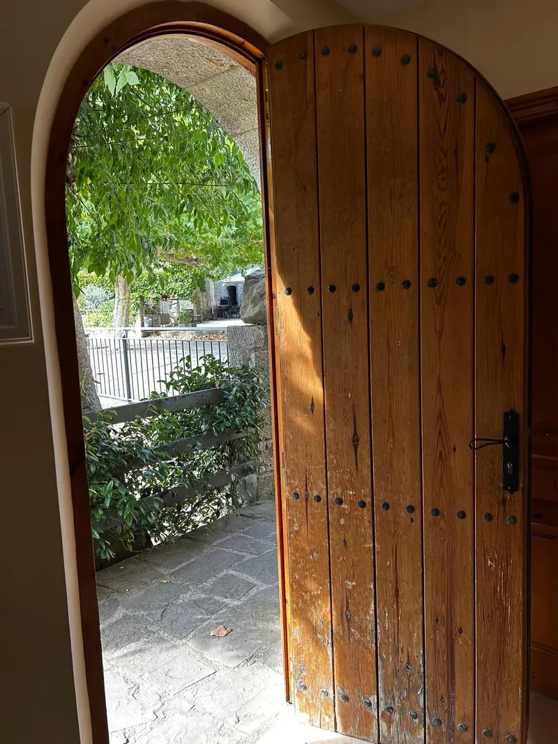 Arched wooden door open to the outside